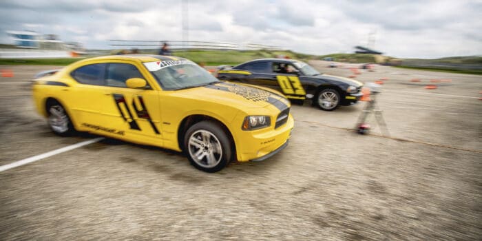 Twee deelnemers in Dodge Chargers strijden tegen elkaar in de dragrace om de overwinning op Circuit Zandvoort tijdens een Race Experience.