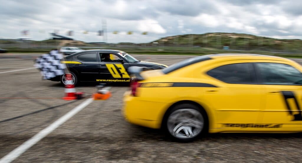 Dragrace tijdens een Race Experience van Bleekemolens Race Planet op Circuit Zandvoort waarbij twee deelnemers tegen elkaar racen in Dodge Chargers.